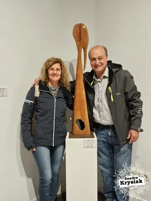 Dos personas junto a Sol y sombra juvenil en una exposición