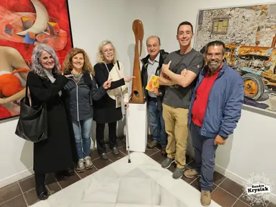 Grupo en una exposición junto a una escultura y un diploma