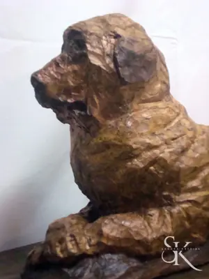 Perro tallado en madera, tumbado con las patas delanteras extendidas