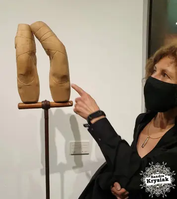 Escultura de madera clara y metal con forma de arco