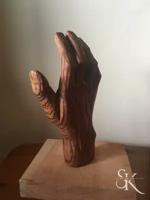 Mano abierta tallada en madera sobre una base cuadrada