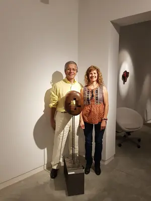 Dos personas junto a una escultura circular expuesta