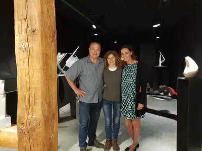Tres personas junto a una escultura alta