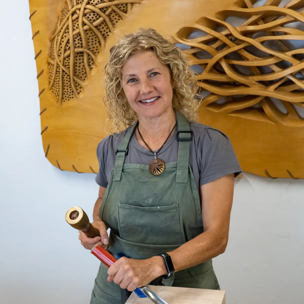 Sandra Krysiak tallando en su taller, con un bloque de madera sujeto al banco