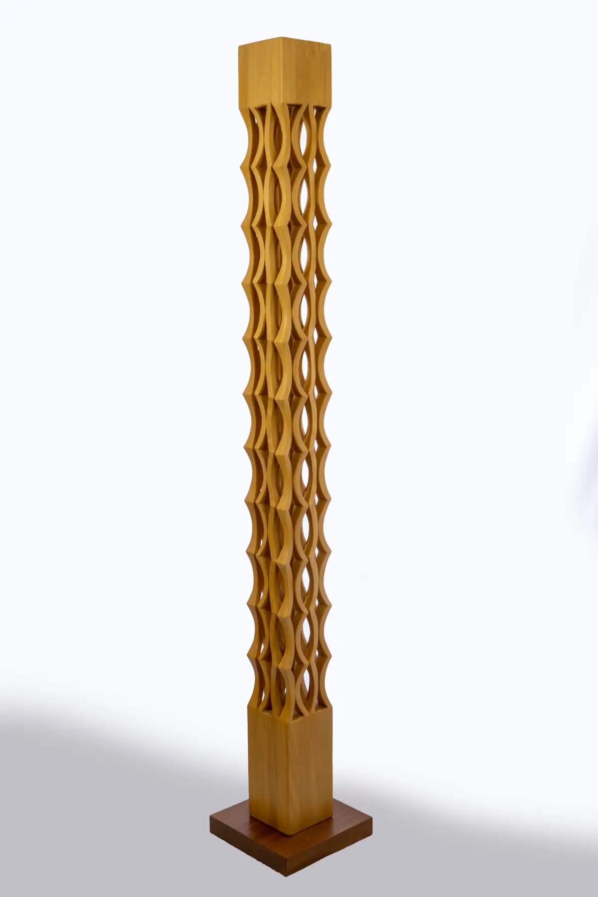 Columna vertical de ayous tallada con formas angulosas repetidas que se cruzan, sobre peana cuadrada de madera oscura