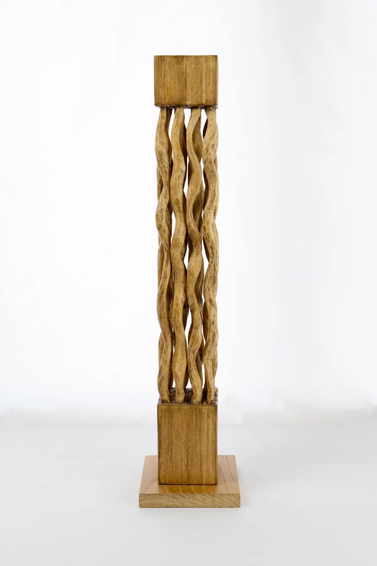 Columna vertical de ayous formada por cordones de madera entrelazados, montada sobre una peana cuadrada