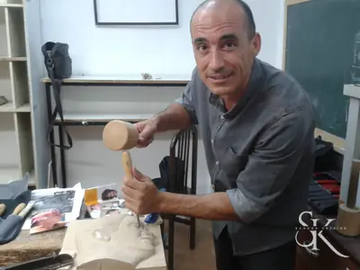 Alumno con mazo y gubia frente a su talla