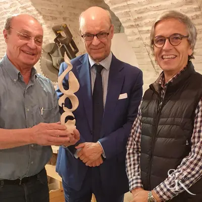 Tres personas sostienen una pieza tallada