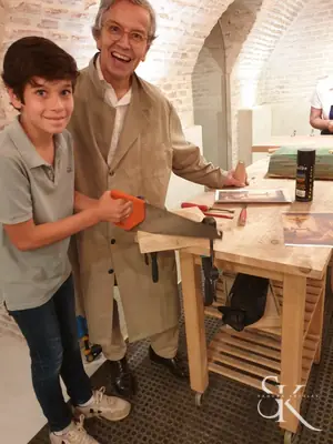 Dos alumnos con mazos junto a una pieza