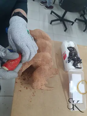 Manos con guantes trabajando una pieza de madera