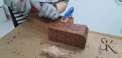 Manos con guantes desbastando un bloque