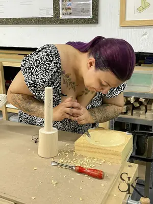 Alumna concentrada tallando con mazo y gubia
