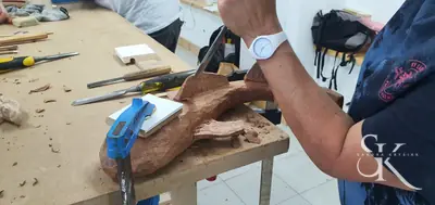 Manos trabajando una forma curva sobre el banco