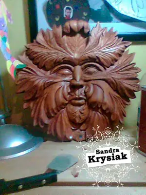 Rostro de madera rodeado de hojas