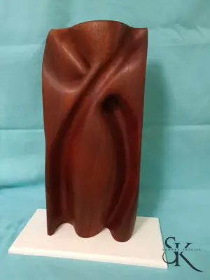 Escultura de madera rojiza con líneas curvas