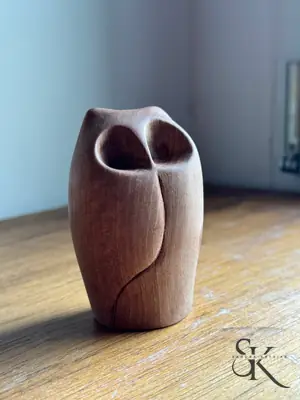 Pieza de madera rojiza con dos aberturas en la parte superior