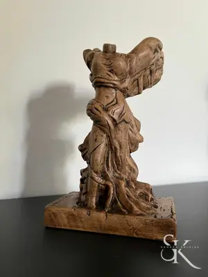 Escultura de madera rojiza sobre una base rectangular