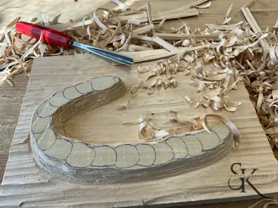 Pieza de madera en proceso de talla, rodeada de virutas
