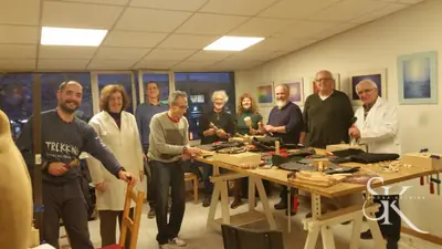 Grupo de alumnos alrededor de una mesa con gubias, mazos y piezas en proceso
