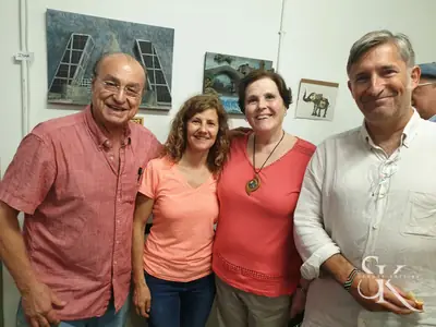 Participantes del taller sonríen junto a varias piezas talladas en madera