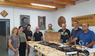 Grupo de alumnos reunido alrededor de la mesa de trabajo del taller