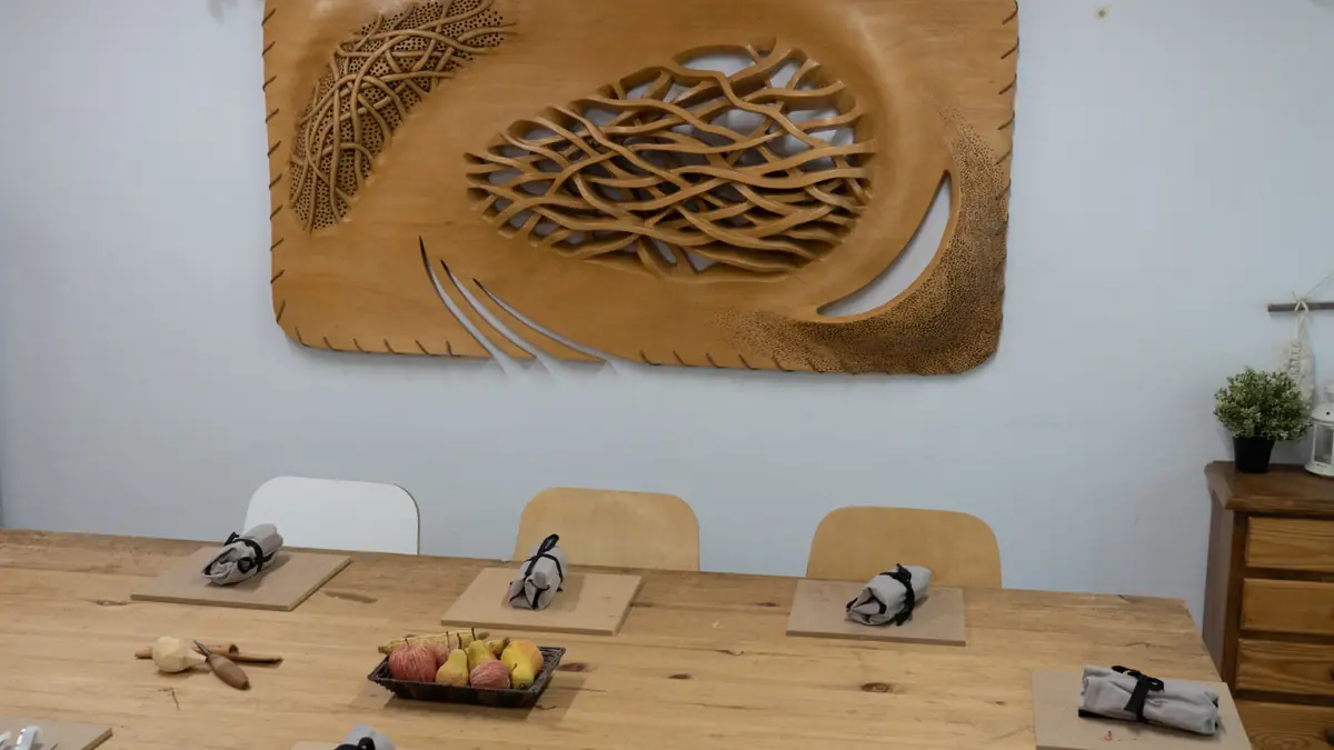 Sala del taller de Guadarrama con las mesas preparadas y un gran relieve tallado en la pared