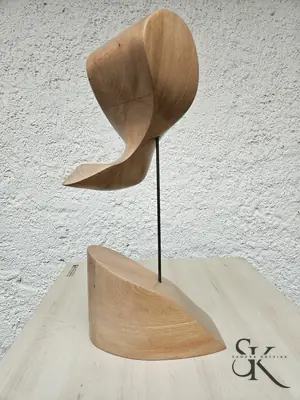 Escultura de madera clara con dos formas curvas sobre una base