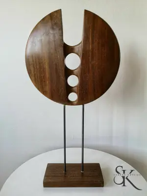 Escultura circular de madera con aberturas, sostenida por dos varillas