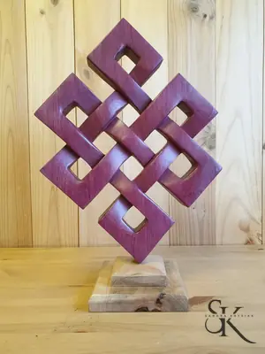 Escultura geométrica de madera teñida en tonos burdeos sobre una base