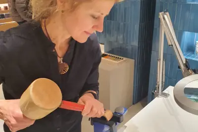 Sandra Krysiak talla con mazo y gubia una pieza sujeta en un tornillo de mesa, en el mostrador de Loewe de El Corte Inglés