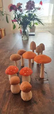 Setas talladas en madera y pintadas en tonos naranjas y marrones, colocadas sobre una mesa