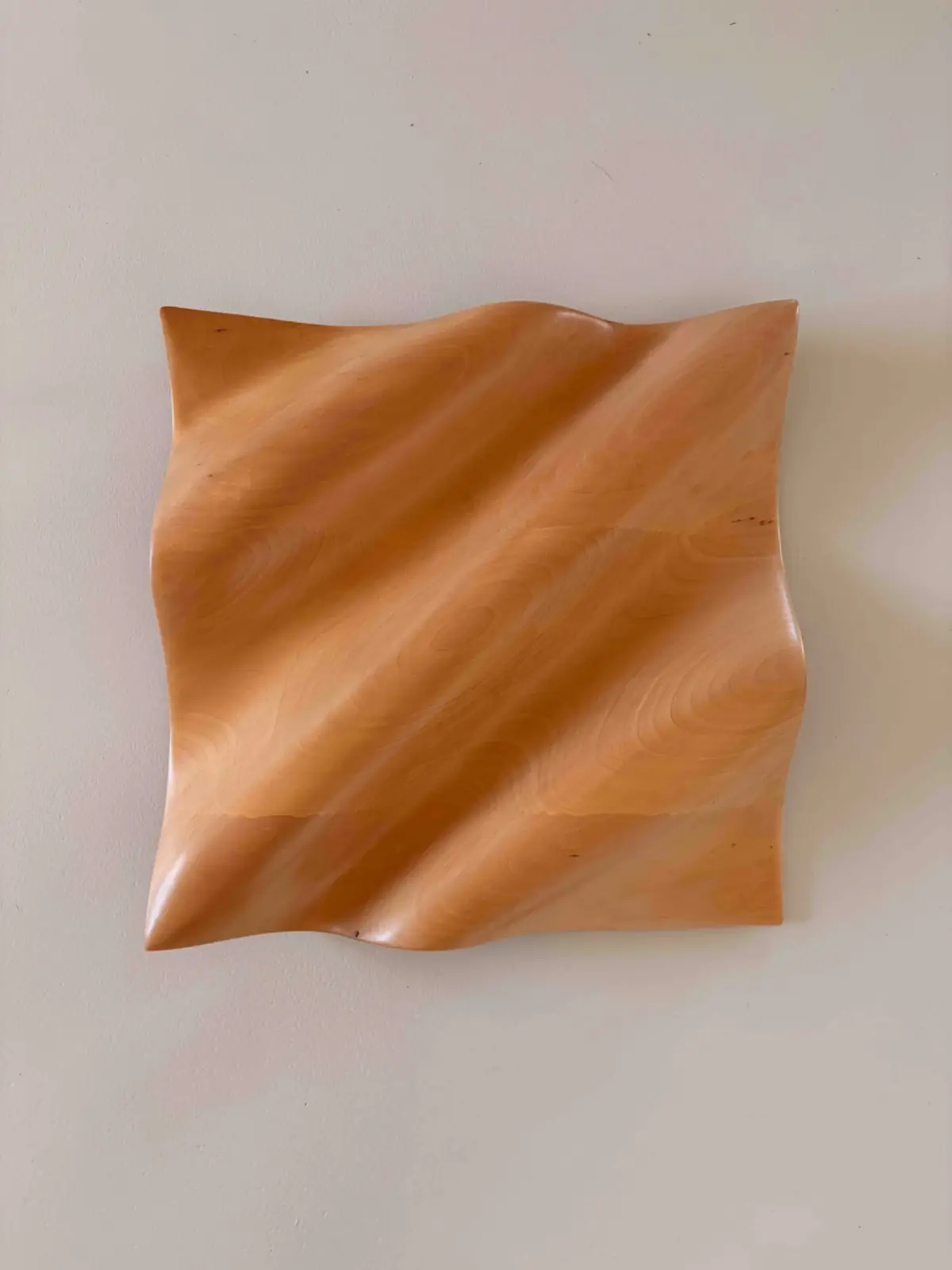 Relieve de madera de tilo con formas onduladas en diagonal, colgado en una pared clara