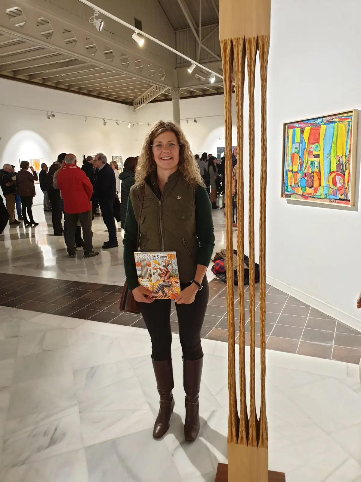 Sandra Krysiak con el catálogo en la mano, junto a su columna «Bosque interior» en la sala del Salón de Otoño