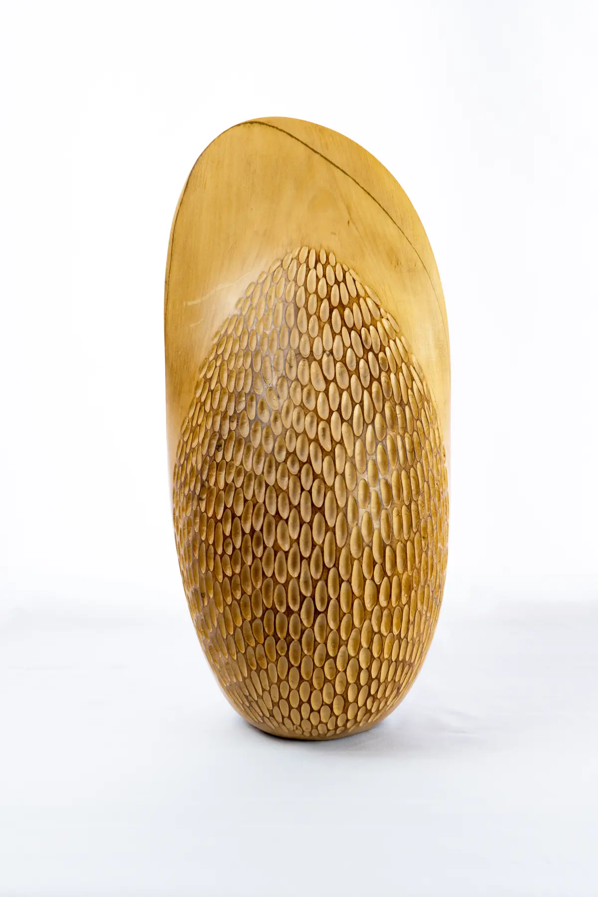 Escultura de tilo con forma de semilla, con una cara tallada en escamas superpuestas